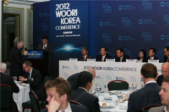 우리투자증권은 6월 11일(런던 현지시간) 런던 챈서리코트호텔에서 ‘2012 우리 코리아 컨퍼런스’를 개최했다. 한 외국인 투자자가 우리금융그룹 IR세션(회사소개) 에서 우리금융그룹의 현황에 대해 질문하고 있다. ‘2012 우리 코리아 컨퍼런스’는 국내 18개 기업이 참석해 미주 및 유럽권 주요 해외 기관투자가들에게 한국의 우량 기업들을 소개하는 자리이다. (사진 테이블 좌측부터 김양진 우리은행 수석부행장, 황성호 우리투자증권 사장, 이팔성 우리금융그룹 회장, 통역담당자, 송기진 광주은행장, 이병재 우리파이낸셜 대표이사)