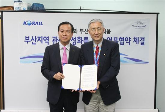 안승언(왼쪽) 부산역장과 김영필 아쿠아리움 대표이사가 협약서를 펼쳐보이고 있다.