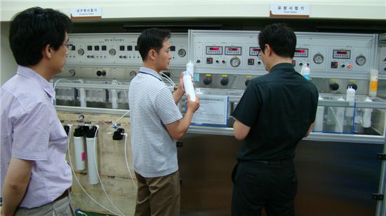 환경기술연구소장(왼쪽)과 필터솔루션팀 직원이 생산과정에서 유량시험기와 내구력시험기 등을 통해 필터를 검사하는 방법에 대해 설명하고 있다.