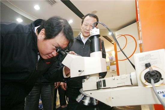 SK하이닉스 중국공장을 방문한 최태원 SK그룹 회장이 현미경을 통해 반도체 회로를 들여다보고 있는 모습. 사진 오른쪽은 권오철 SK하이닉스 대표. 