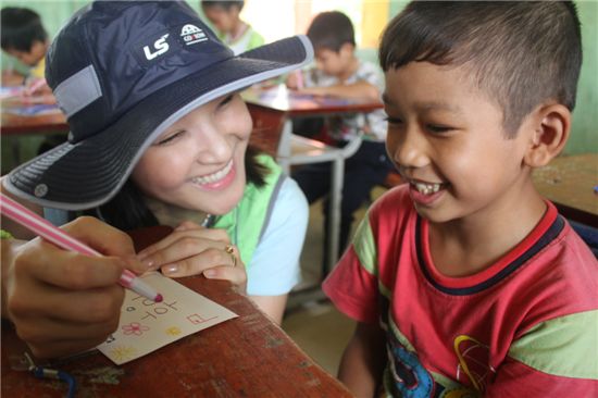 LS 대학생 해외봉사단원이 베트남 아이를 가르치며 환하게 웃고 있는 모습 
 