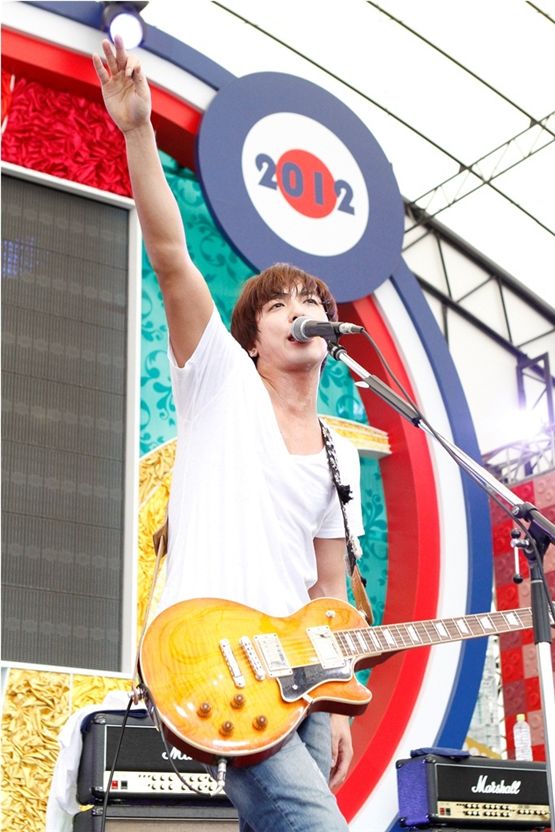 CNBLUE's leader, vocalist and guitarist Jung Yong-hwa, donned in a plain white tee shirt and jeans, raises his arm up high while singing at Mezamashi Live, in Tokyo on August 28, 2012. [FNC Entertainment]