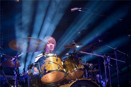 FTIsland's drummer Choi Min-hwan, donned in a white tee shirt, plays the drums during their concert "TAKE FTISLAND," which took place at Seoul's Olympic Hall on September 1 and 2, in front of several thousand fans. [FNC Entertainment]