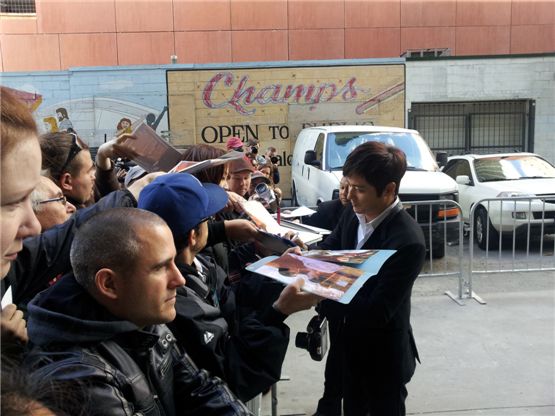 Korean actor Jang Dong-gun (right) signs his autograph for fans at the 37th Toronto International Film Festival in Toronto, Canada on September 10, 2012. [Cine De Epi]