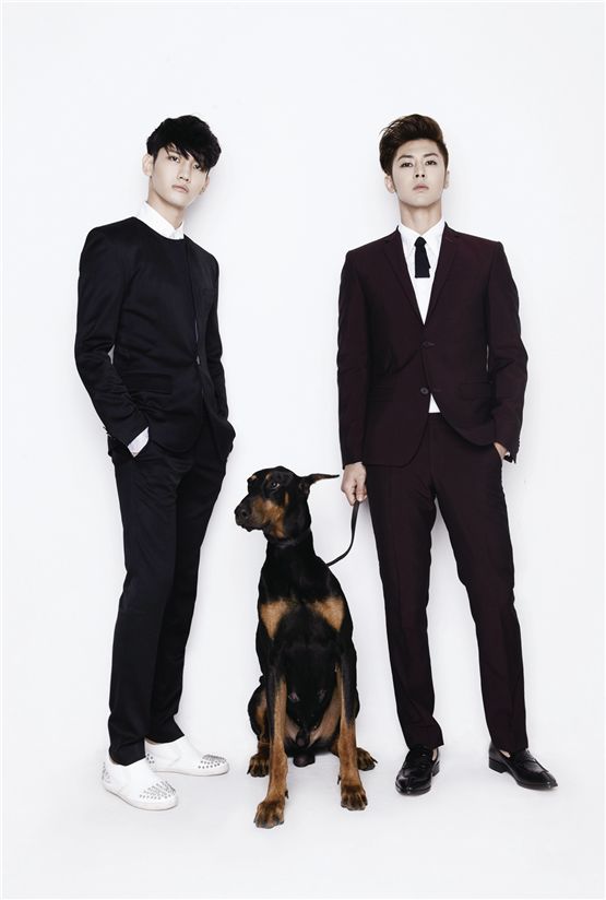 TVXQ!'s Max Changmin (left) and U-Know Yunho (right), both donned in black suits, pose with a dog for a group shot to promote their upcoming world tour "TVXQ! LIVE WORLD TOUR 'Catch Me,'" which will take place at Seoul's Olympic Stadium on November 17 and 18. [SM Entertainment] 