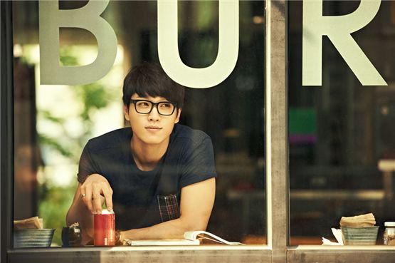 Singer Lee Seok-hoon, donned in a navy blue shirt, poses for a picture taken a coffee shop. [Jellyfish Entertainment]