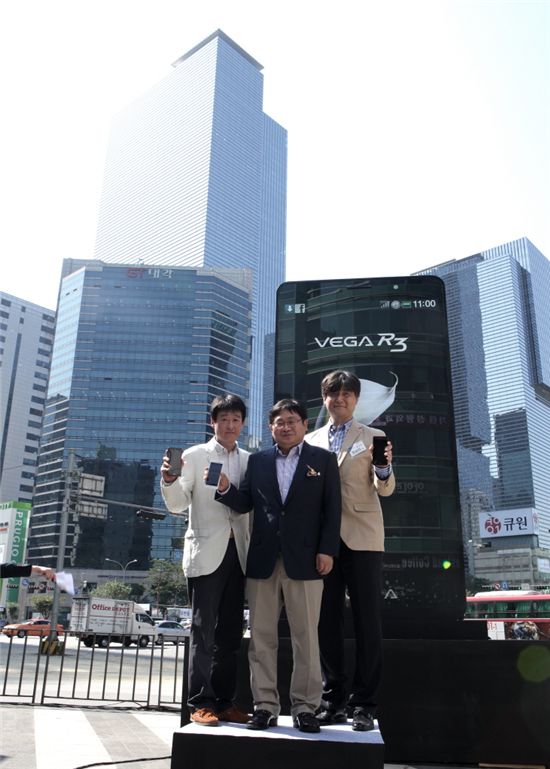 팬택이 24일 서울 강남역 인근 M스테이지에서 베가 R3 출시 행사를 가진 가운데 이준우 팬택 부사장(가운데)이 높이 6m의 베가 R3 조형물을 공개하는 제막식을 거행했다. 베가 R3 조형물 뒤로 삼성전자 본사 사옥이 보인다.