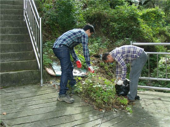 집 주위의 잡초를 베고 쓰레기를 치우는 양산국유림관리소 직원들