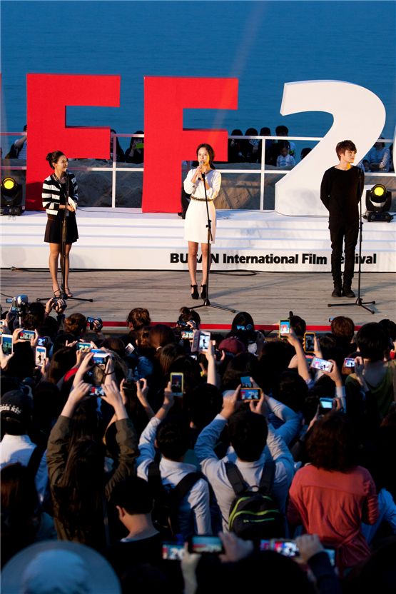 Korean actress Song Ji-hyo (center) and singer-actor Kim Jae-joong (right) of boy band JYJ pose in front of crowds at the 17th Busan International Film Festival's Outdoor Stage in Haeundae BIFF village in Busan, South Korea, on October 5, 2012. [Lee Jin-hyuk/ 10Asia]