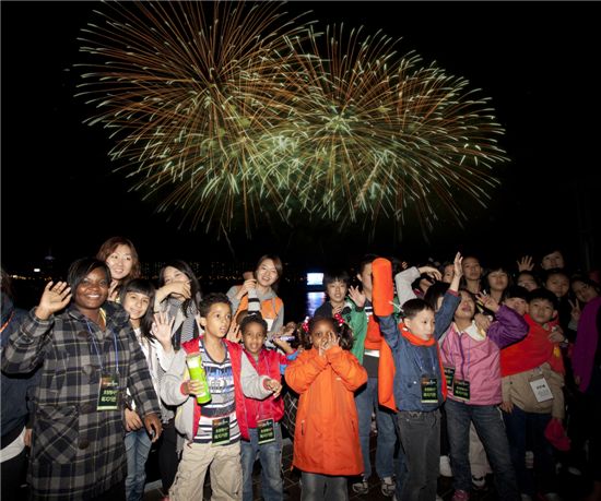 한화그룹의 서울세계불꽃축제에 초대된 다문화가족, 소년소녀가장들이 한강 선상카페에서 불꽃쇼를 배경으로 기념촬영을 하고 있는 모습. 