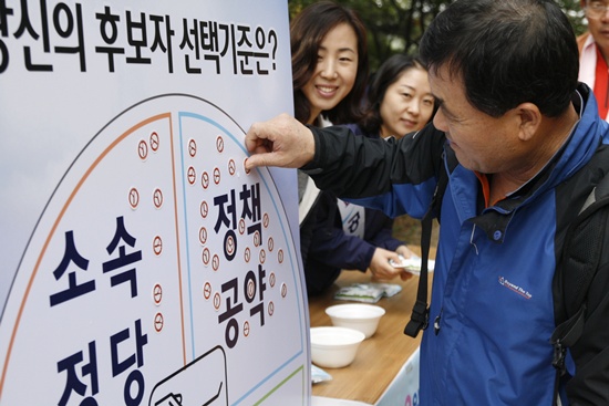 계족산 맨발축제에 참여한 한 시민이 대전광역시선거관리위원회가 만든 투표참여홍보판에 스티커를 붙이고 있다.