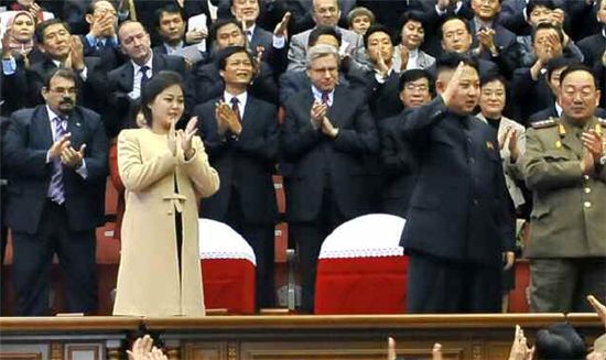 북한 김정은 당 제1비서(앞줄 가운데)와 리설주(왼쪽)가 29일 모란봉악단 행사에 참석해 손을 흔들고 박수를 치면서 주민호응에 답하고 있다.(출처:노동신문)