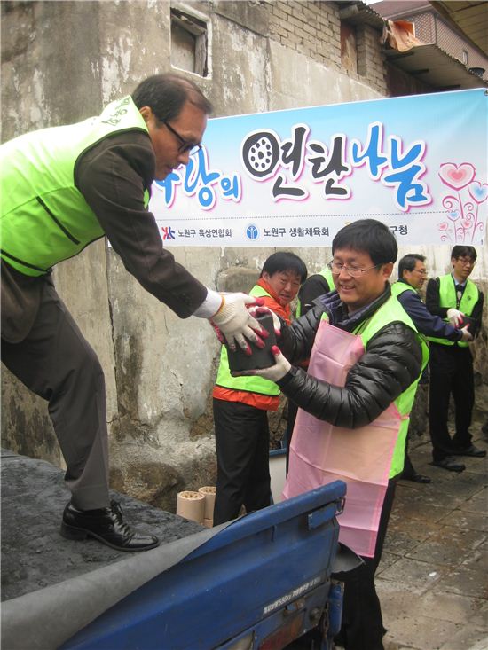 김성환 노원구청장이 봉사자들과 함께 사랑의 연탄 나르기 행사에 참가해 땀을 흘리고 있다.