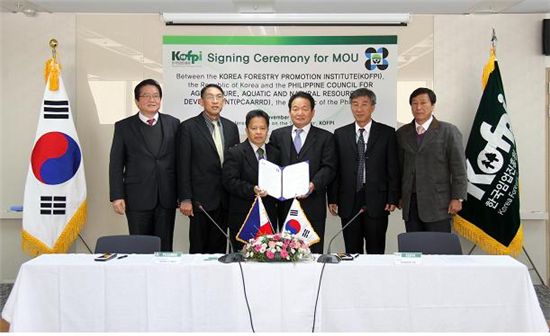 이동섭(왼쪽에서 4번째) 한국임업진흥원장이 필리핀 PCARRD와 '공동연구 및 기술협력 MOU'를 체결한 뒤 협약서를 펼쳐들고 관계자들과 기념사진을 찍고 있다.