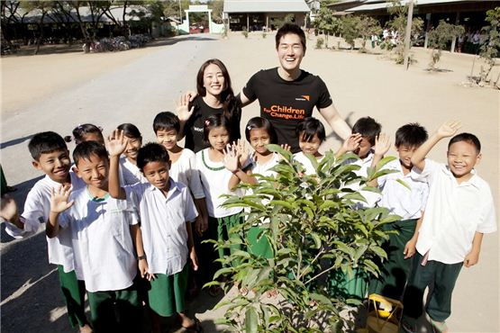 Actress Kim Hyo-jin (left) and Yoo Ji-tae (right) pose together amongst students they have been giving help for one year in Myanmar in the picture released by Namoo Actors on December 5, 2012. [World Vision]
