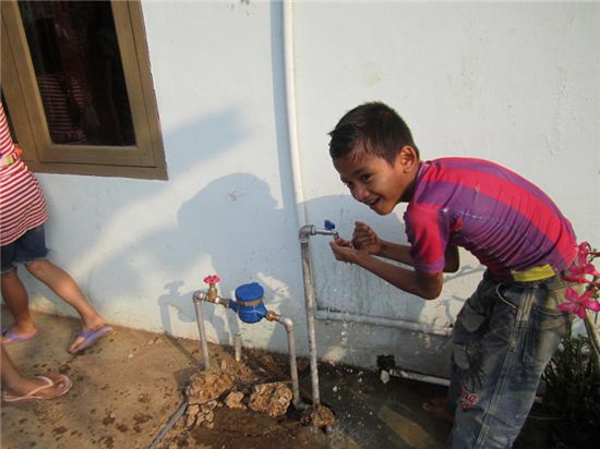▲동양매직의 식수시설 지원사업을 받은 지역 어린이가 물을 이용하고 있다(사진 회사제공) 