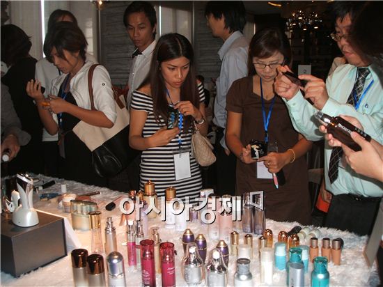 태국 화장품 업체 관계자들이 ㈜연우가 전시한 화장품 용기들을 관찰하고 있다.