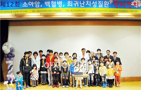 화순전남대병원은  47명 완치자에게  축하 메달을 걸어주고  어린이들과 국훈 병원장 등 관계자들이 기념촬영을 하고 있다.