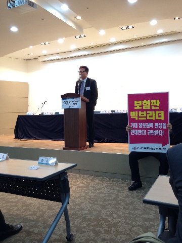 김대식 보험연구원장이 21일 개회사를 진행하는 동안 사무금융노조 관계자가 보험정보 일원화를 반대하는 피켓을 들고 항의표시를 하고 있다.