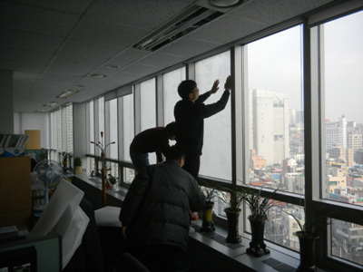 성북구 환경과 직원들이 에너지 절약을 위해 창문에 단열시트를 붙이고 있다.