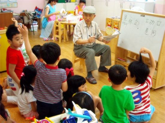 어르신이 유치원에서 아이들에게 한자를 가르치고 있다.