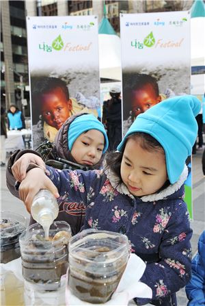 하이트진로음료가 세계 물의 낮을 맞아 진행한 '나눔水 페스티벌'에서 아이들이 정수 분말을 이용한 정수 체험을 하고 있다.
