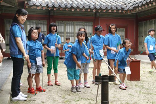 신한은행 자원봉사자들이 1박2일 창경궁 궁중생활 문화체험 행사에서 다문화 가정 아동들과 함께 전통놀이인 투호던지기를 하고 있다.