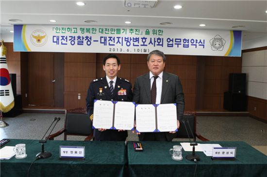 정용선(왼쪽) 대전지방경찰청장과 문성식 대전지방변호사회장이 협약서를 펼쳐들고 포즈를 잡고 있다.