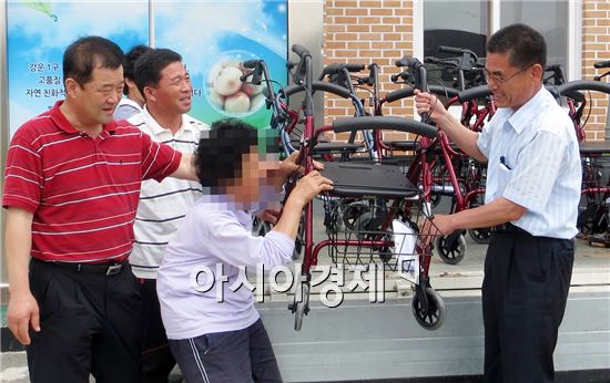 김강남 함평군 대동면장(맨 오른쪽)이 관내 노인에게 보행보조차를 전달하고 있다.
