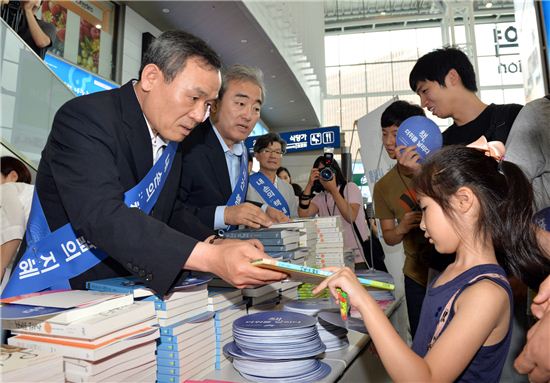 2일 유진룡 문화체육관광부 장관(왼쪽에서 두번째)와 신충식 NH농협은행장(왼쪽에서 첫번째)이 서울역과 용산역에서 '책 나눔행사'를 갖고 시민들에게 책을 나눠주고 있다.
