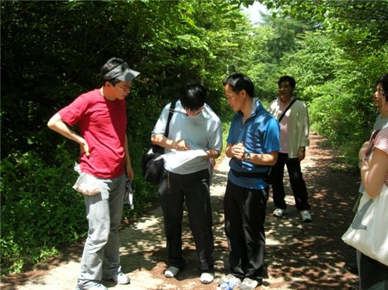 휴양림 숲에서 지도와 나침반을 갖고 목표지점을 찾고 있는 오리엔티어링대회 참가자들