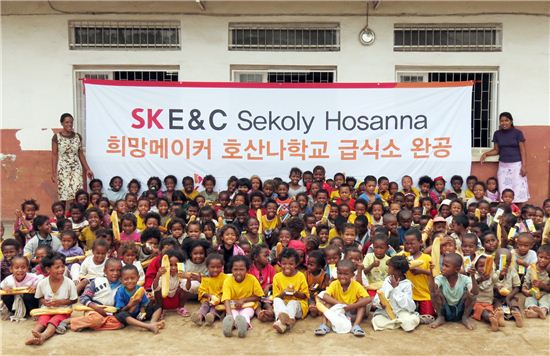 ▲SK건설은 지난 2월 마다가스카르 수도 안타나나리보 근교의 미션호산나주말학교에 2층 규모의 급식소를 지어 기부했다. 새롭게 지어진 급식소 앞에서 학생들이 기념촬영을 하고 있다.