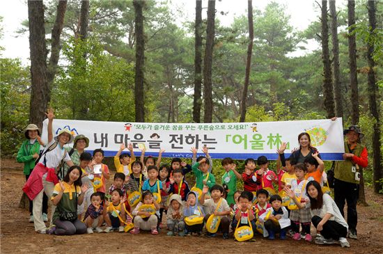 숲에서 펼쳐지고 있는 ‘마음과 마음의 어울林’ 캠페인 행사에 참여한 유치원생들이 선생님들과 기념사진을 찍고 있다.