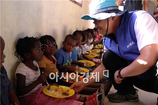 삼성중공업 직원이 모잠비크 어린이에게 급식을 나눠주고 있다.(사진제공=삼성중공업)
