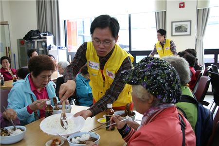 모과균 광동제약 부사장(가운데)이 강원 원주에 위치한 밥상공동체 행복센터에서 노인 분들에게 자장면을 나눠주고 있다.