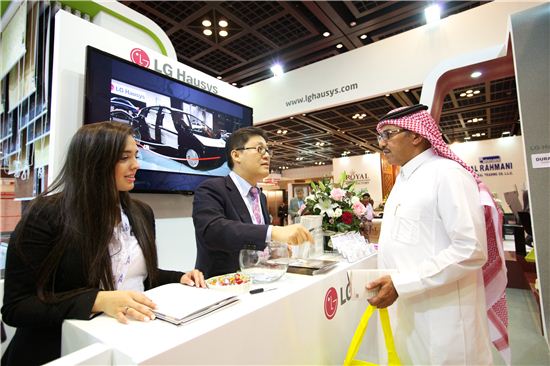 LG하우시스 직원이 두바이 국제 건축자재 박람회에서 전시관을 방문한 고객에게 제품을 설명하고 있는 모습 .