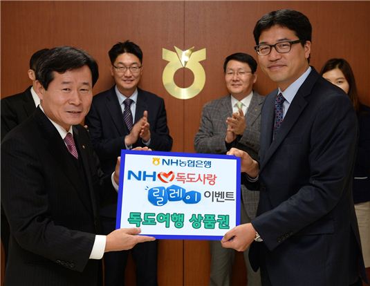 임승택 농협은행 안양시지부장(왼쪽)이 김윤우 고객에게 독도여행상품권을 전달하고 있다.