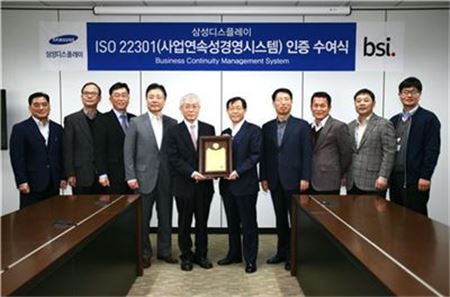 ▲삼성디스플레이는 8일 충남 아산사업장에서 사업연속성경영시스템에 대한 국제표준인 ISO 22301인증 수여식을 개최했다고 밝혔다. 이선용 삼성디스플레이 아산/천안 단지총괄 부사장(중앙 오른쪽)이 천정기 BSI(영국표준협회) 코리아 회장(중앙 왼쪽)과 인증서를 교환하고 있다.