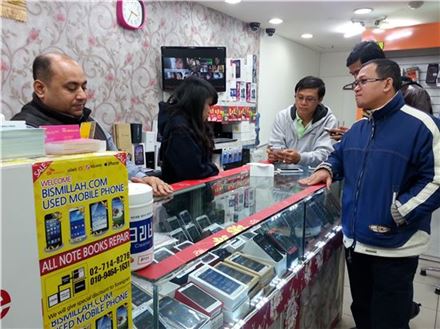 서울 용산 휴대폰 할인상가에 문을 연 한 중고폰 판매점에서 지난 15일 외국인 고객이 스마트폰을 만져 보고 있다. 