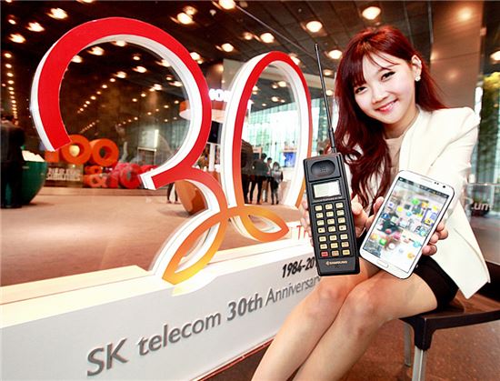 SK텔레콤 관계자들이 27일 서울 을지로 SK텔레콤 사옥에서 과거 이동통신 초창기에 쓰였던 구형 휴대폰과 최신형 스마트폰을 소개하고 있다. SK텔레콤은 오는 29일로 창사 30주년을 맞는다.