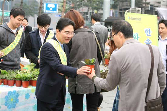 이상훈 한솔제지 대표(왼쪽)가 3일 서울 을지로 사옥 앞에서 시민들에게 화분을 나눠주고 있다.