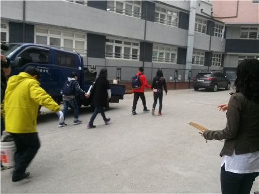 택시를 타고 도착한 명수학교 학생들이 학교 안으로 들어서고 있다.