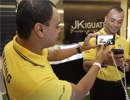 9일(현지시간) 브라질 상파울루에서 열린 '갤럭시 11 월드투어'에 참석한 브라질 전 국가대표 축구선수 (사진 왼쪽)카푸와 데니우손이 전시된 갤럭시 S5를 직접 사용해 보고 있다. 
