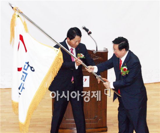 신임 김윤세 위원장(왼쪽)이 이정재 전임 위원장으로부터 당기를 전달 받고있다.