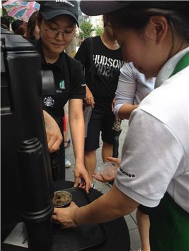 ▲ 스타벅스커피 홍대갤러리점에서 직원들이 고객들에게 아이스커피를 무료로 나눠주고 있다. 