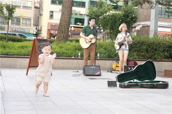 한 어린이가 버스킹 공연이 좋은 듯 박수를 보내고 있다.