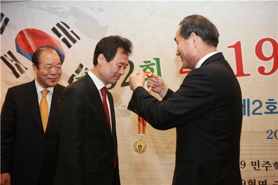 박겸수 강북구청장(가운데)가 박승춘 국가보훈처장으로부터 4.19혁명 봉사대상 메달을 받고 있다.