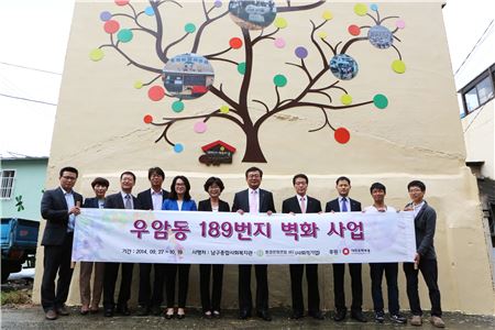 부산 남구 우암동 189번지에서 진행된 '189 벽화마을' 조성에 참여한 관계자들이 20일 마을의 역사를 상징하는 역사나무 앞에서 벽화사업 완료 기념사진을 촬영하고 있다. 

