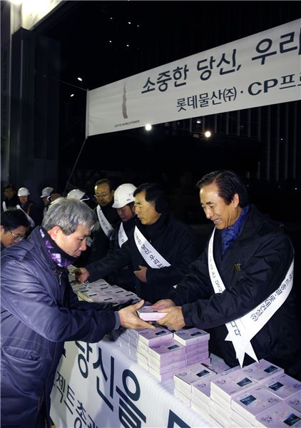 롯데물산 노병용 대표이사(맨 오른쪽)와 임직원들이 2일 롯데월드타워 공사 현장 입구에서 새해 첫 출근을 하는 현장 근로자들에게 '복떡'을 건네며 안전 시공을 당부하고 있다. 
