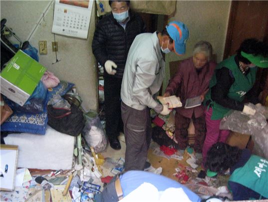 ▲지난해 10월 서울시 서대문구 홍제1동의 함모(79·여) 할머니의 지하 월셋방에서 자원봉사자·동 관계자들이 쓰레기를 치우고 있다(사진제공=서대문구)